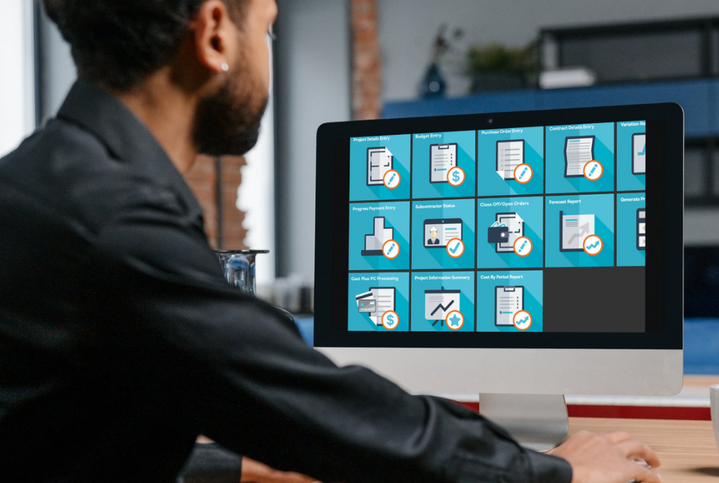 A person sits at a desk, looking at a computer monitor displaying various icons related to document management software.